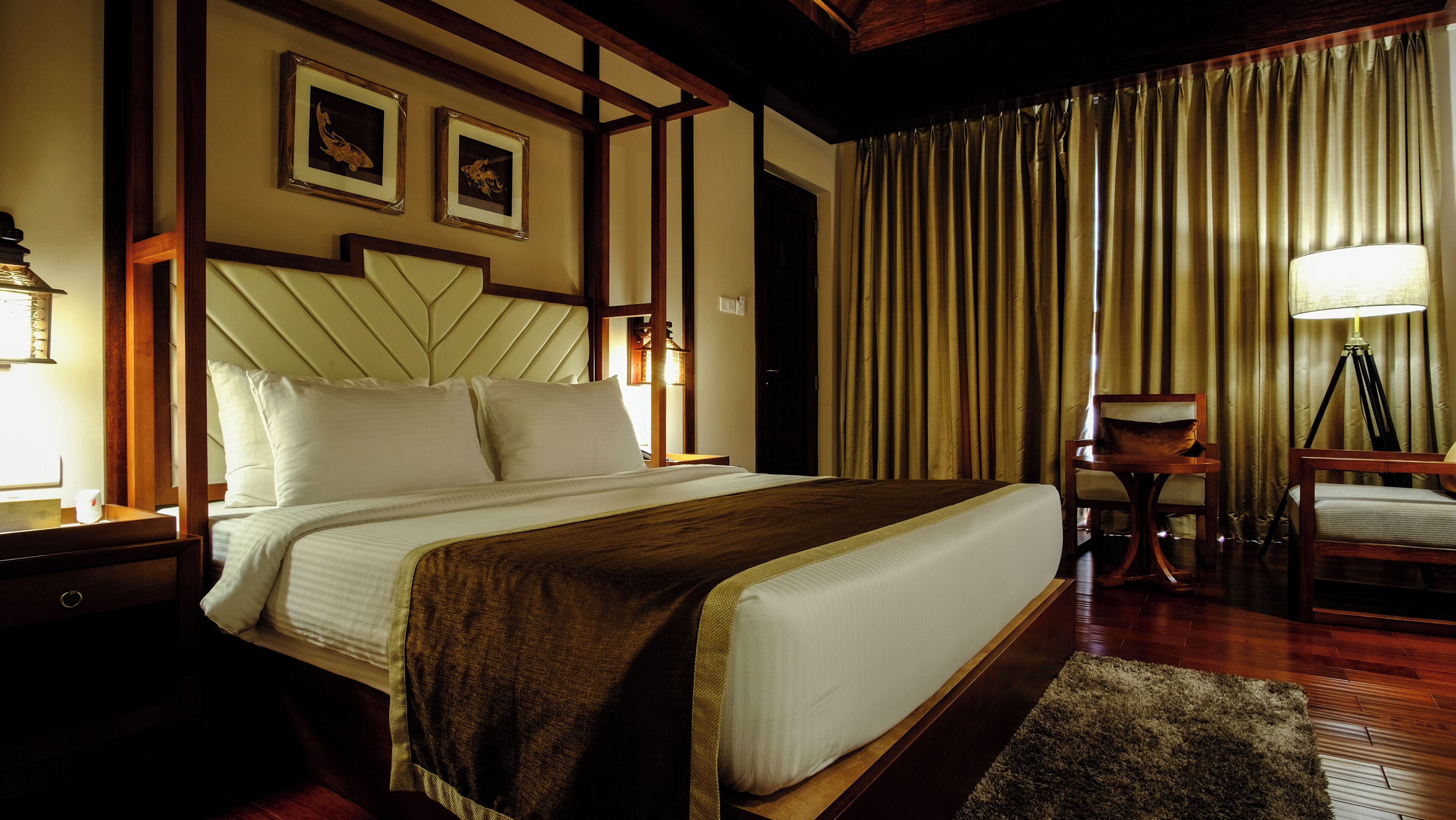 Une chambre d’hôtel avec un grand lit, une tête de lit en bois, un bureau avec une lampe et une chaise.