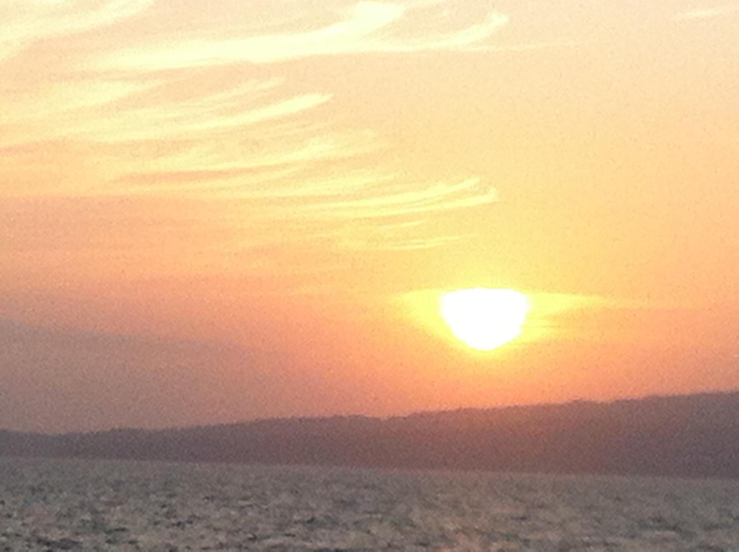 Un coucher de soleil sur un paysage plat, avec un horizon dégagé.