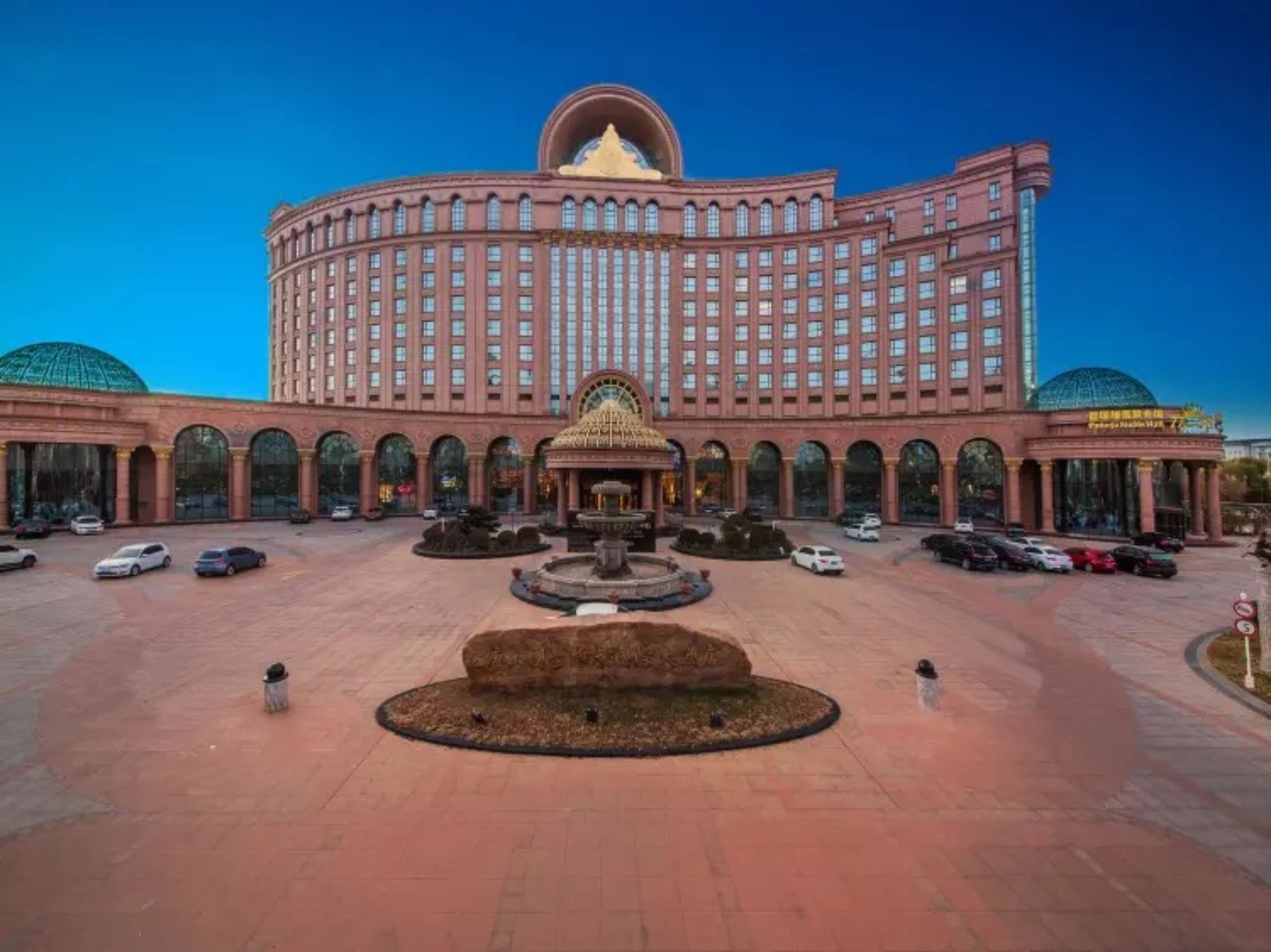 Un hotel grande de varios pisos con un patio central, una fuente y una estructura en forma de cúpula.