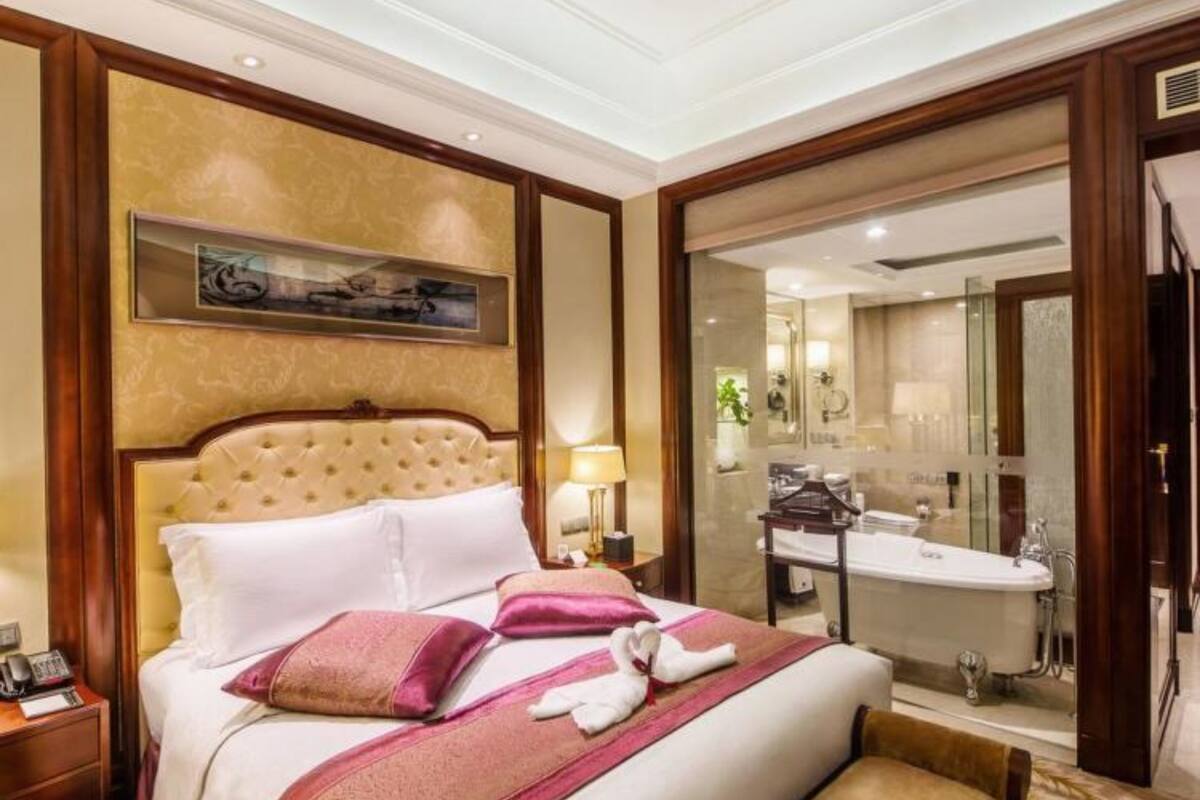 A hotel room with a large bed, a bedside table, a lamp, and a view of the bathroom.