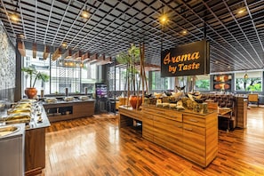 Un intérieur de restaurant moderne avec un plancher en bois, un îlot central agrémenté d’objets décoratifs et une enseigne indiquant « Aroma by Taste ».