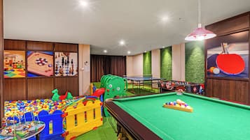 A children's play area with a pool table, colorful toys, and a green carpet.