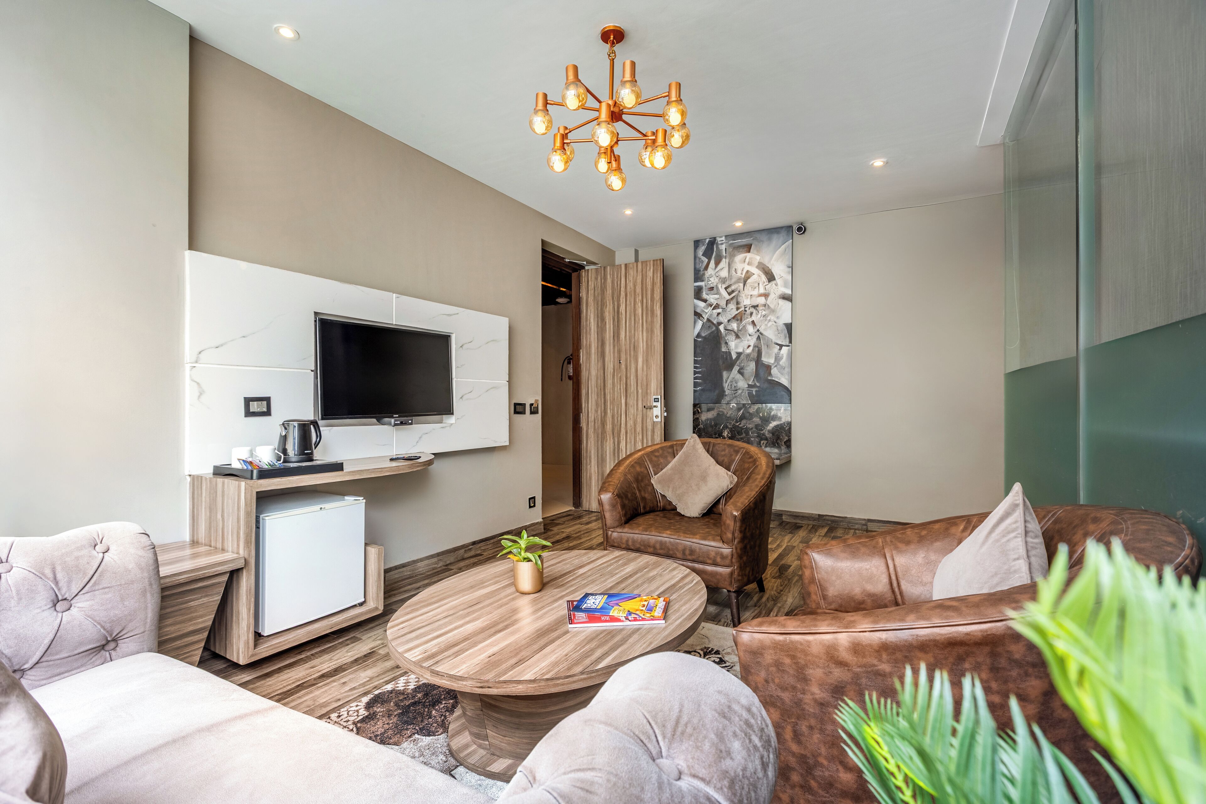 A modern living room with a flat-screen TV, a coffee table, leather sofas, and a wooden floor.