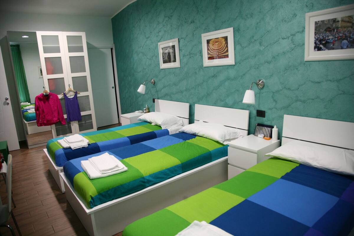 A hotel room with two beds, a wardrobe, and a desk.