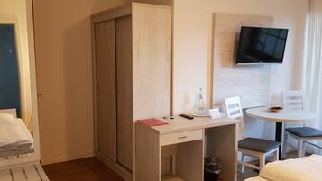 Habitación de hotel con cama, escritorio y silla, televisor montado en la pared y ventana con vistas.