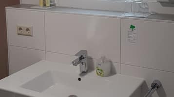 Ein modernes Badezimmer mit einem großen Spiegel, einem weißen Waschbecken und einer Toilette.