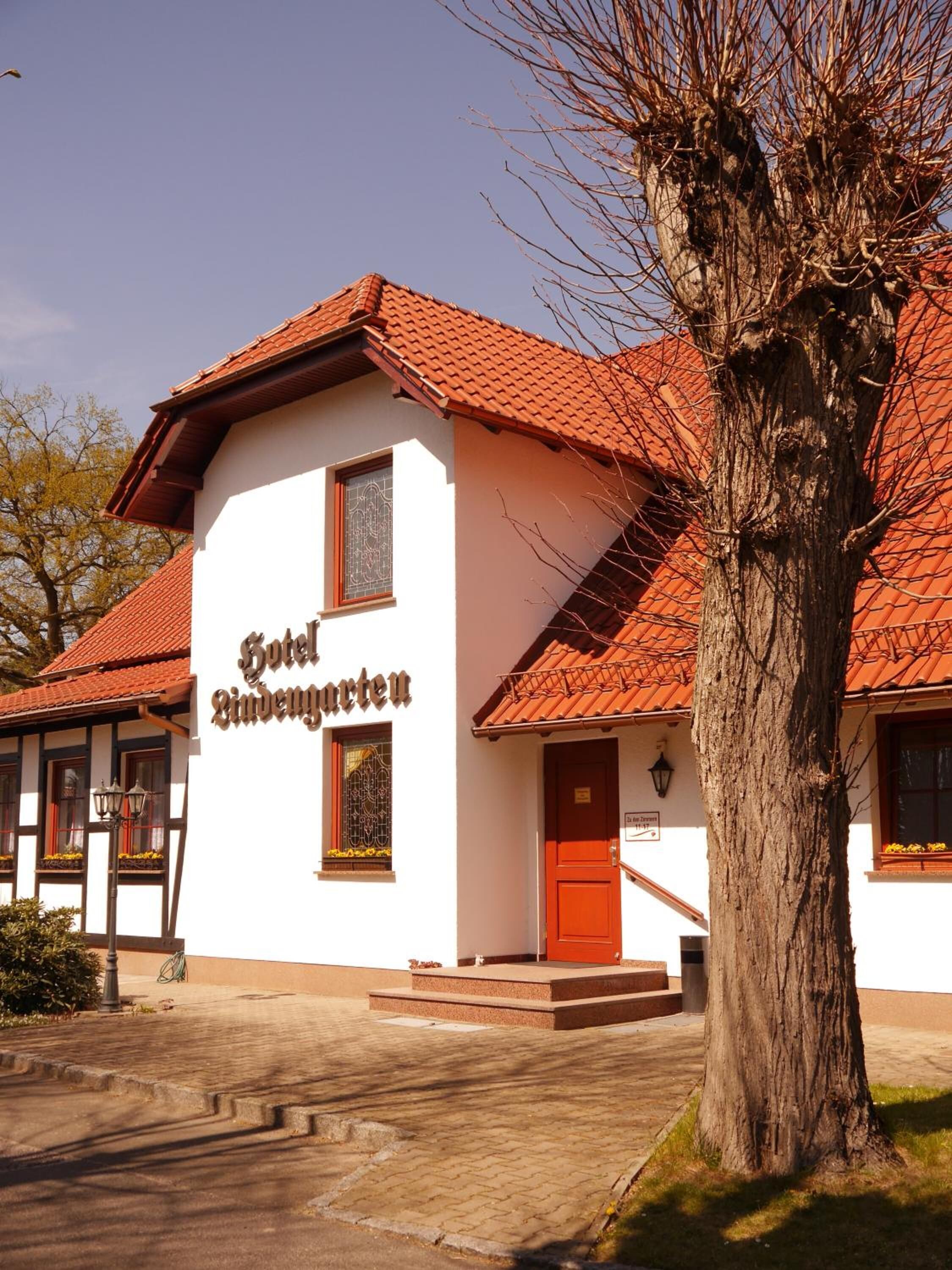 Een wit gebouw met een rood dak en een bord met de tekst 'Hotel Zimmergarten'.