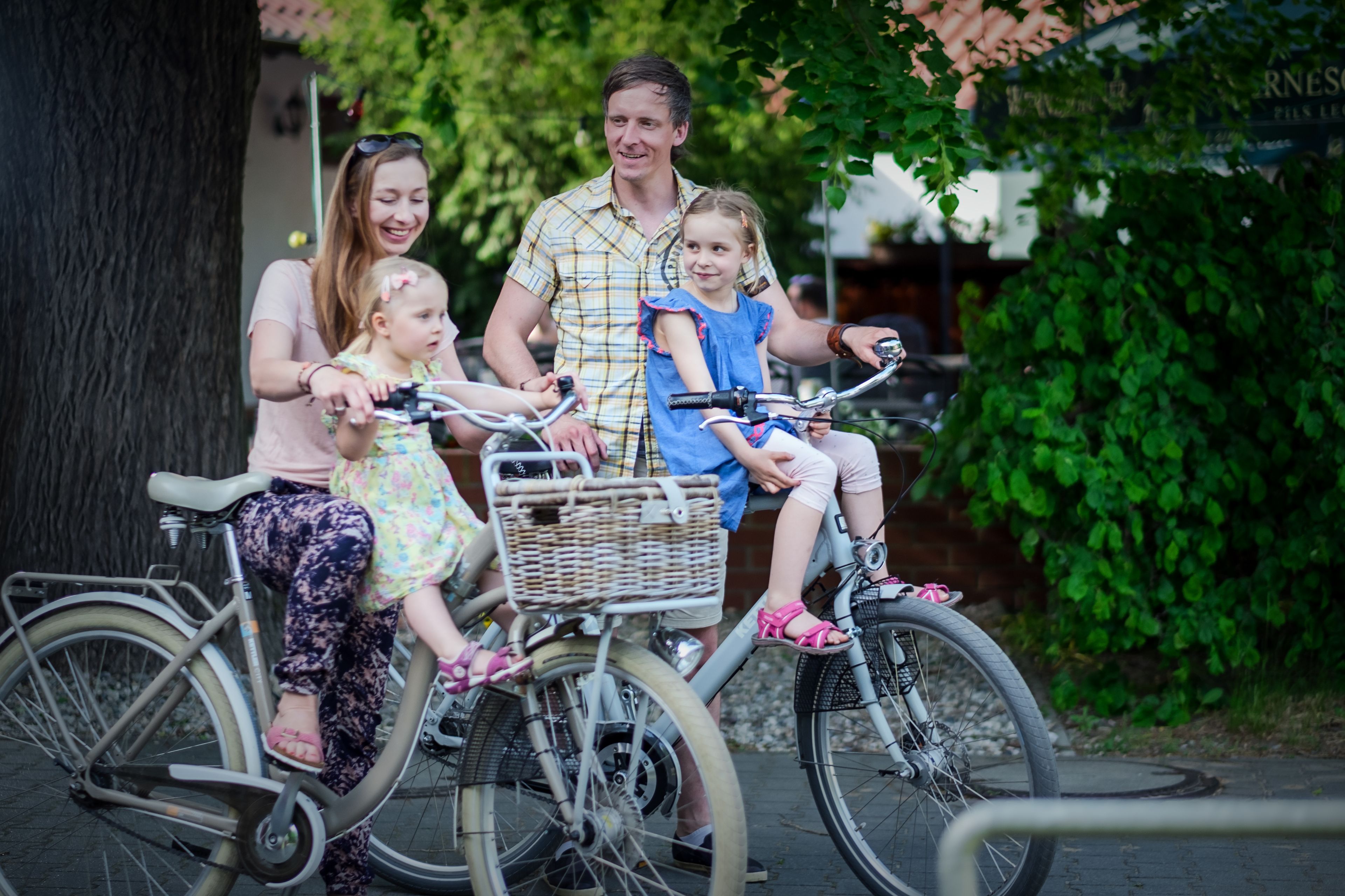 Une famille fait du vélo sur un tandem, avec un panier fixé à l'avant.
