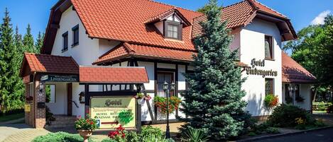 A traditional building with a red-tiled roof, a sign for 'Hotel Restaurant Anzsaal', and a Christmas tree in the front yard.