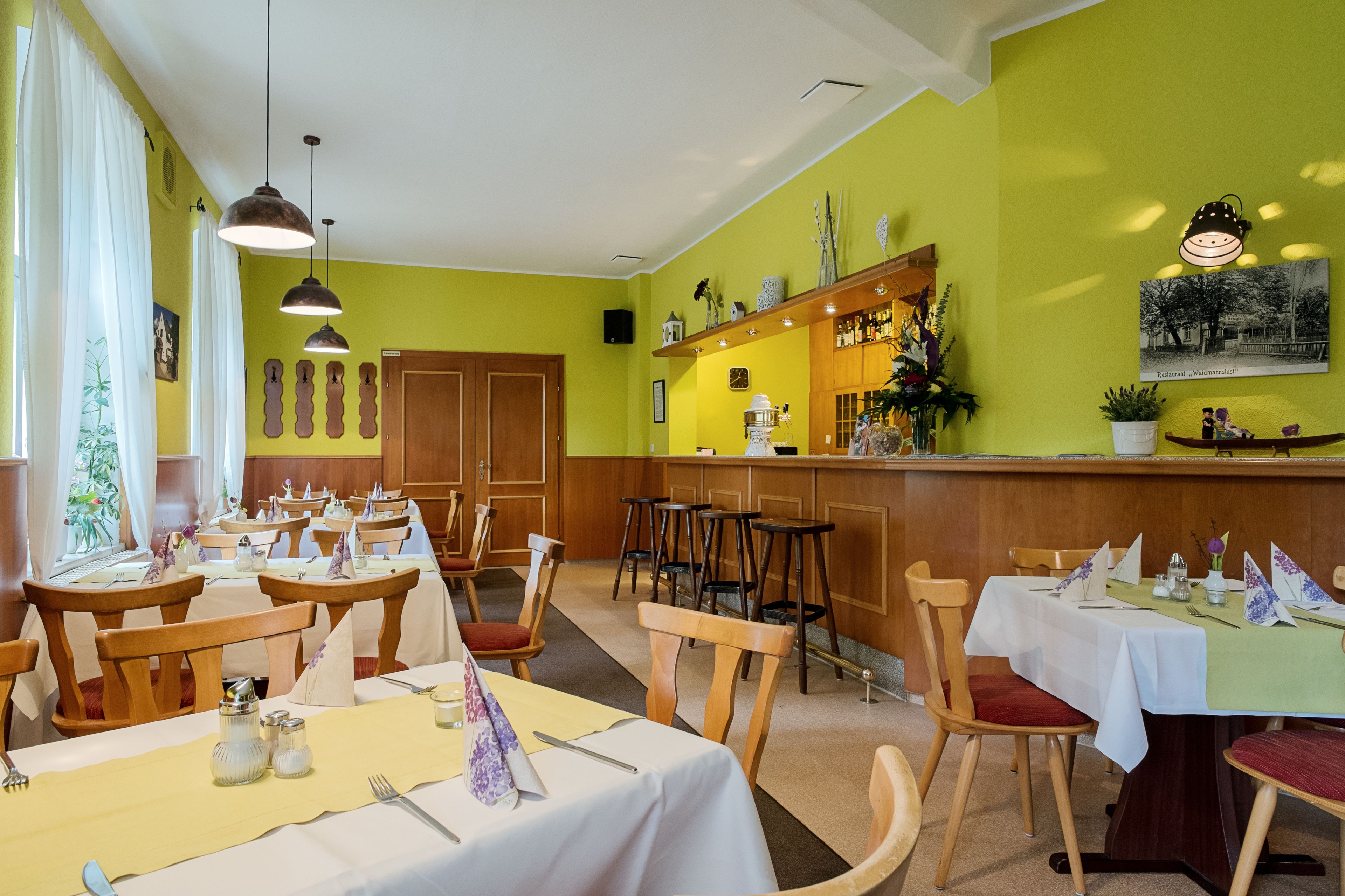 Un restaurant doté de plusieurs tables et chaises, d’un bar et d’un mur orné de divers éléments décoratifs.