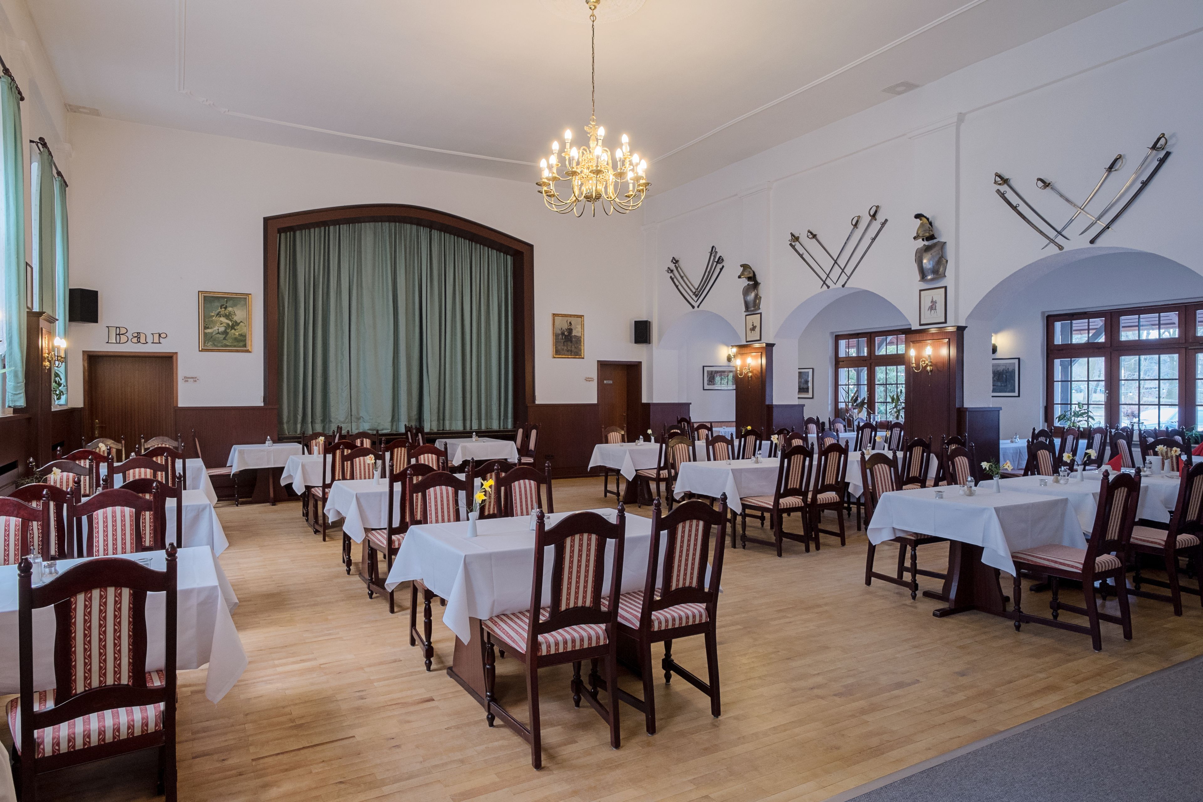Un salón de banquetes con varias mesas y sillas, una araña y decoraciones en las paredes con temática de esquí.