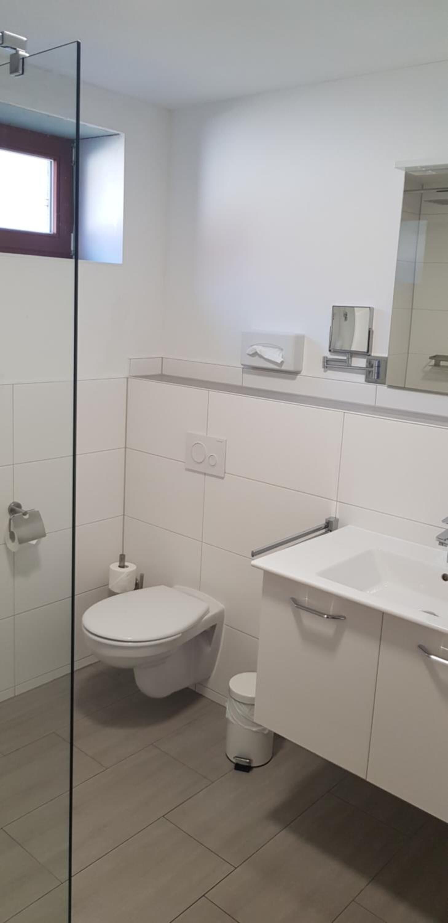 Un baño moderno con inodoro, lavabo y cabina de ducha de vidrio.