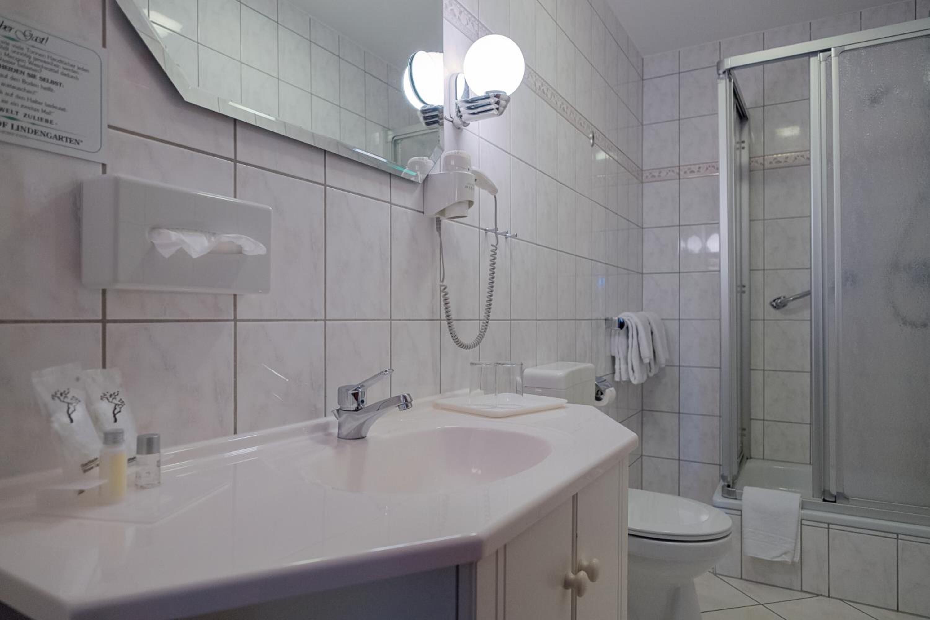 Ein modernes Badezimmer mit einem weißen Waschbecken, einem Spiegel und einer Duschkabine aus Glas.
