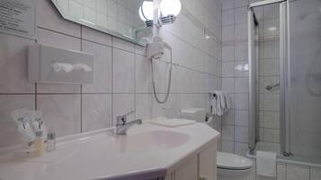 Ein modernes Badezimmer mit einem weißen Waschbecken, einem Spiegel und einer Duschkabine aus Glas.