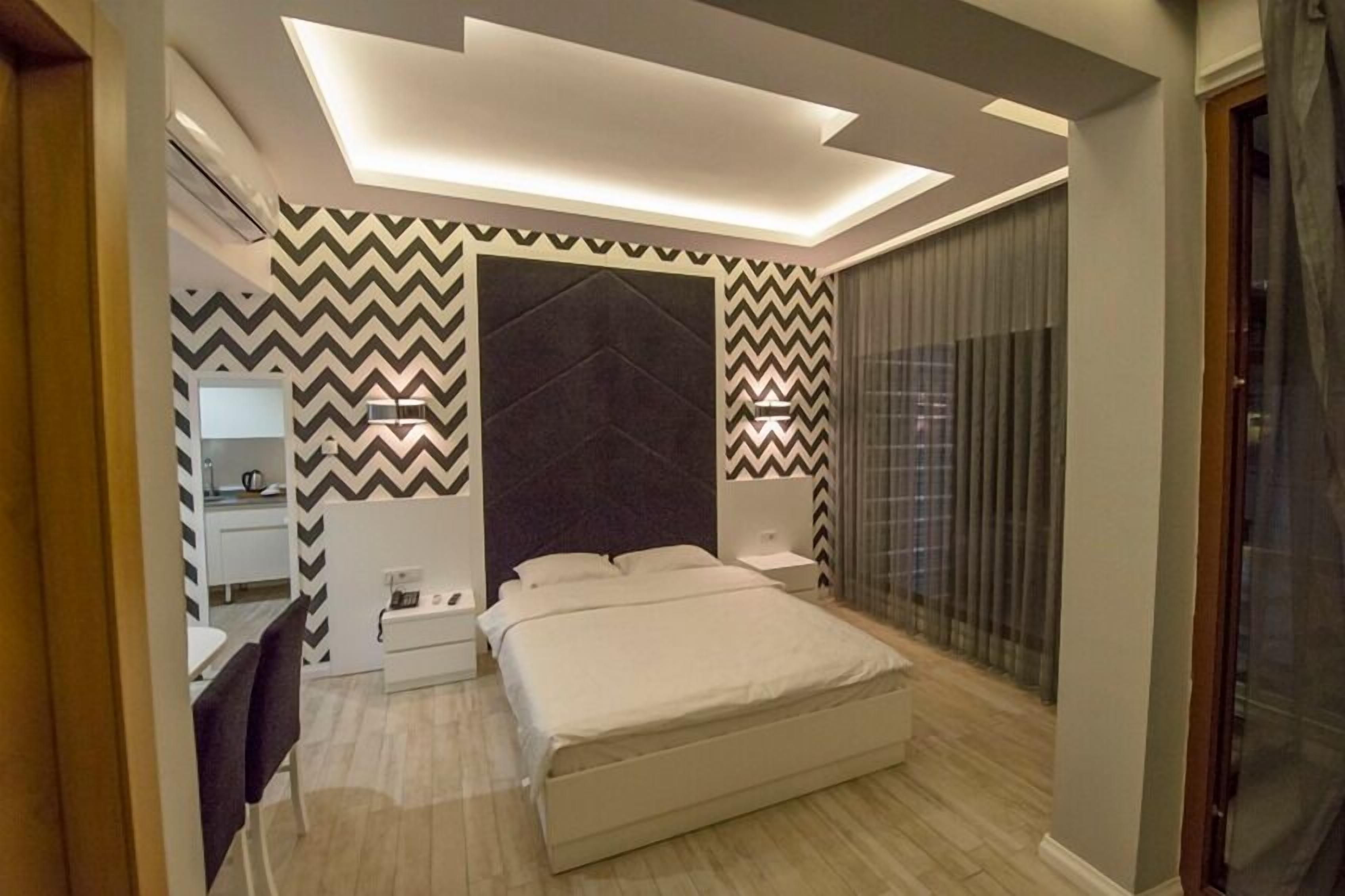 Un dormitorio moderno con cama, mesitas de noche, un escritorio y un espejo.