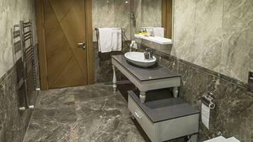 Une salle de bain moderne avec un sol en marbre, un meuble-lavabo à deux vasques, des toilettes et un porte-serviettes.