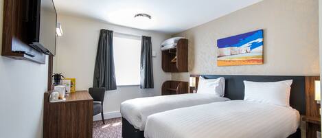 A hotel room with two beds, a desk with a flat-screen TV, a chair, and a painting on the wall.