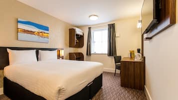 Habitación de hotel con una cama grande, un aparador de madera, un escritorio con silla, un cuadro en la pared y una ventana con cortinas.