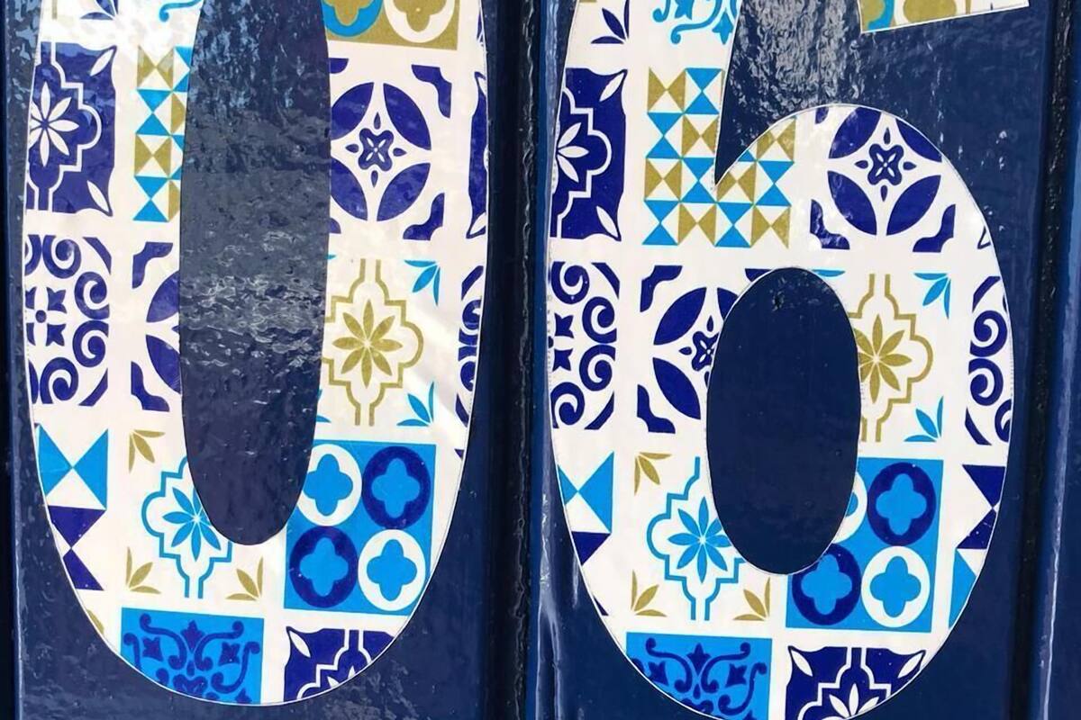 A door with two numbers, 0 and 6, painted in a blue and white tile pattern.