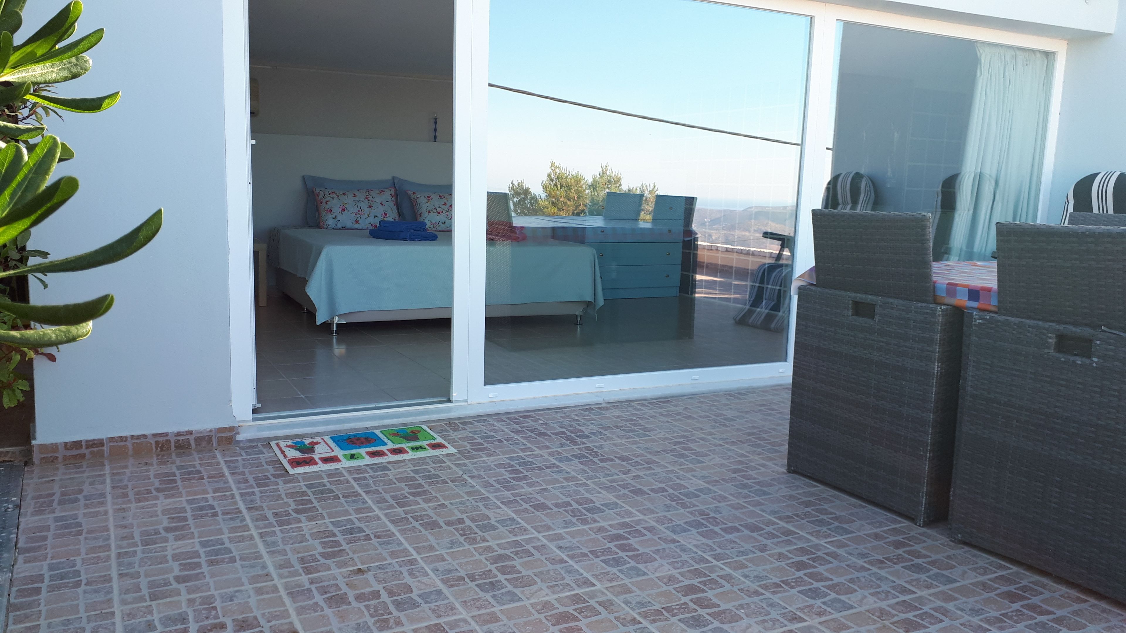 A bedroom with a sliding glass door leading to a balcony.