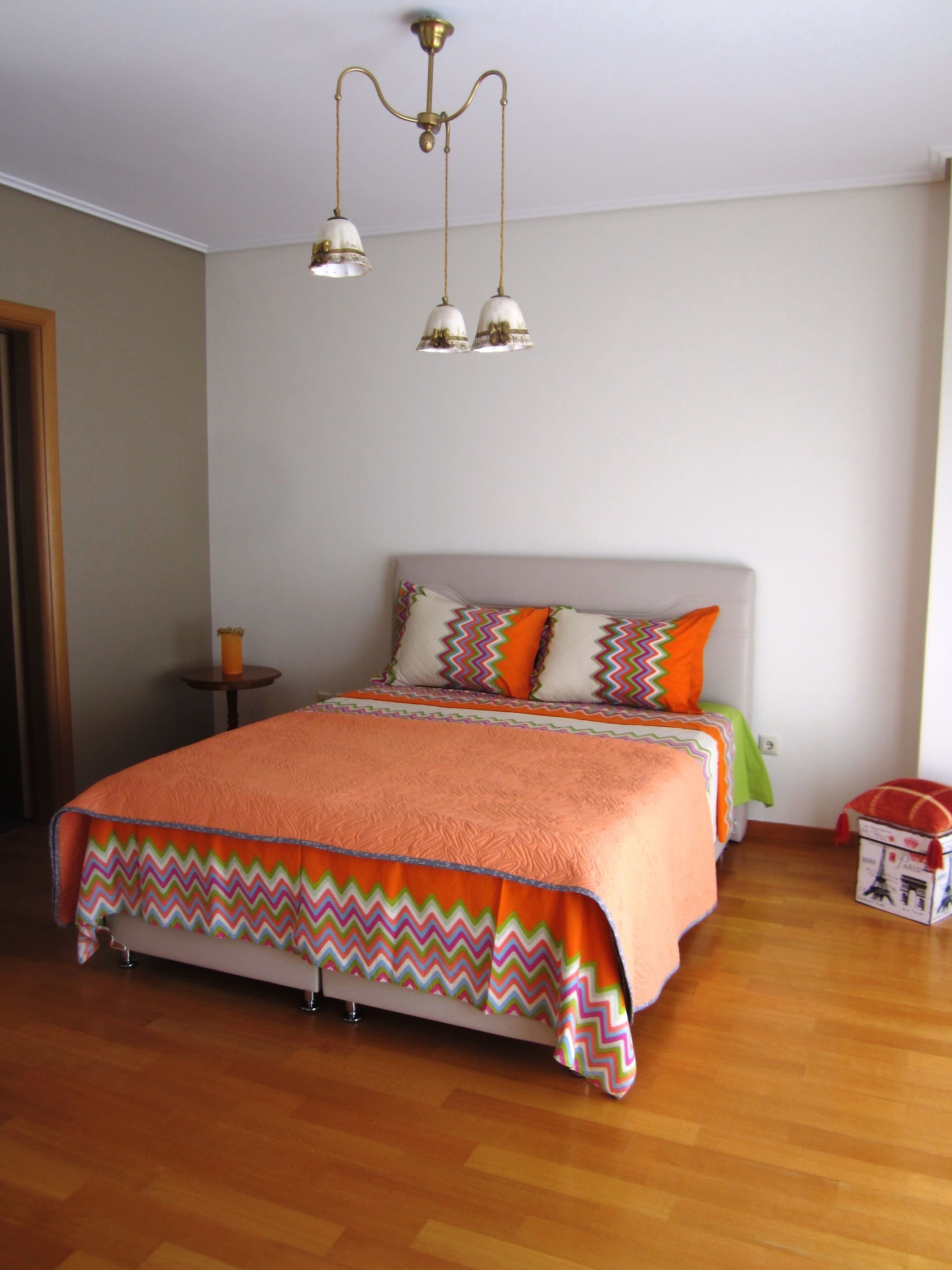 Un dormitorio con una cama, una mesita de noche, una lámpara y un aplique de techo.