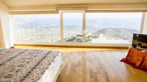 A bedroom with a large window, a bed, a TV, and a small table. - Viva B&B (Saronikos)