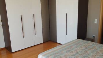 Quarto com cama, soalho de madeira, guarda-roupa e luminárias pendentes.
