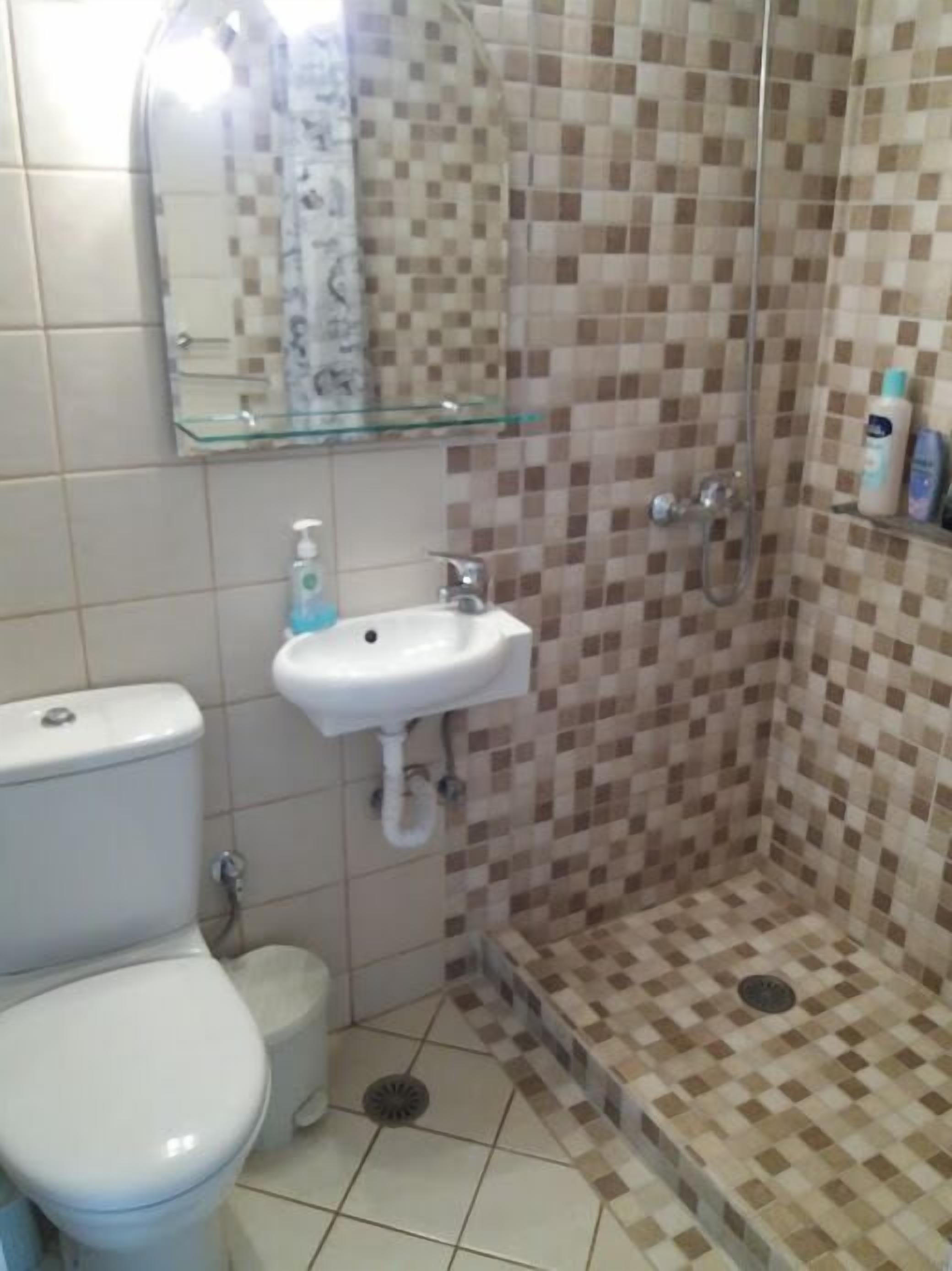 A bathroom with a toilet, sink, and shower.