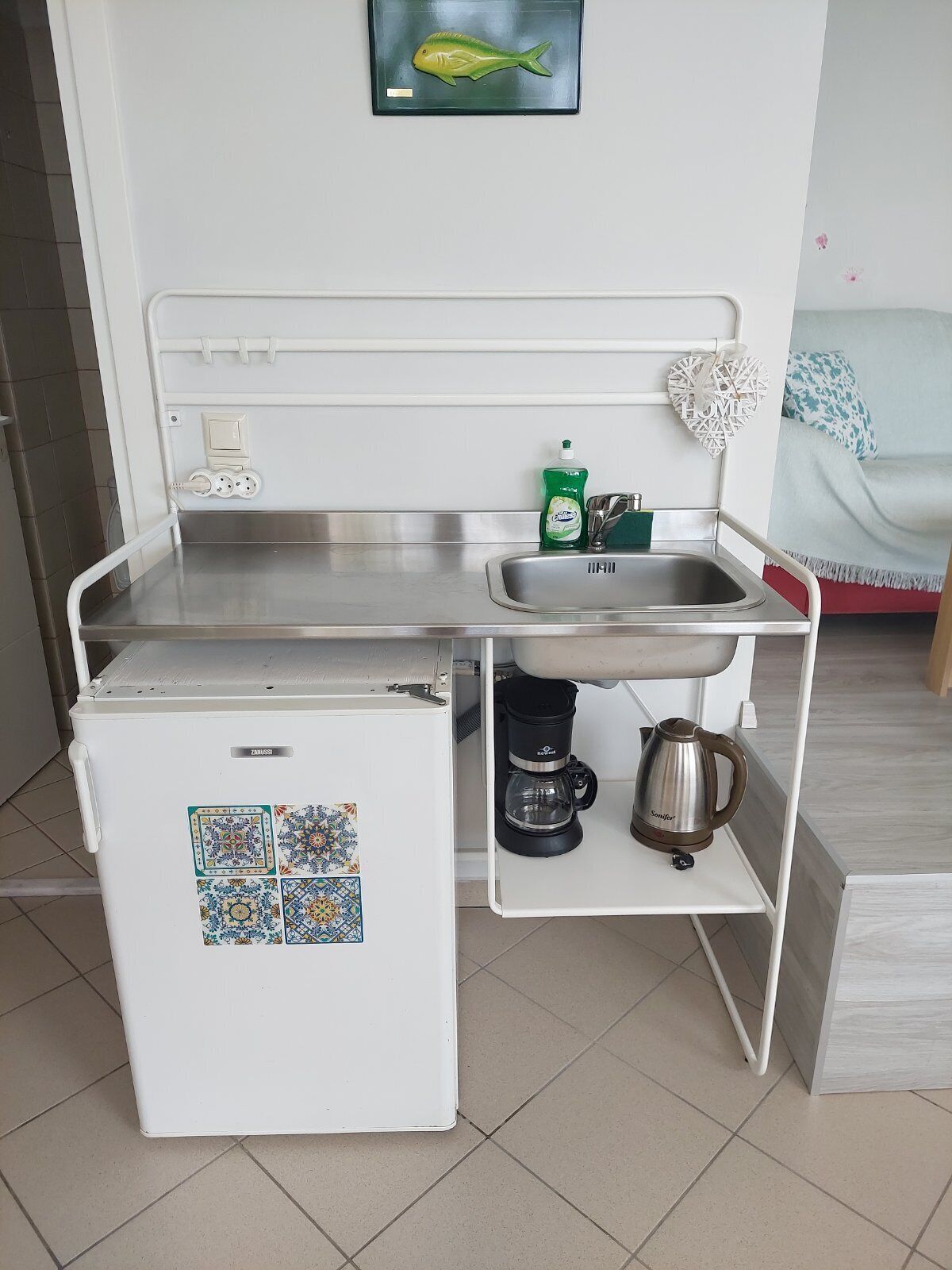 A compact kitchenette with a refrigerator, sink, and coffee maker.