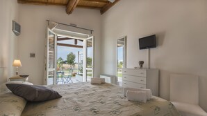 A bedroom with a bed, a TV, a dresser, and a sliding glass door leading to an outdoor area. - Villa Marina Velca (Tarquinia)