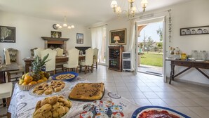 A dining area with a table set for a meal, a fireplace, and a view of the outdoors. - Villa Marina Velca (Tarquinia)
