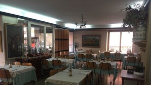 Ein Restaurant mit mehreren Tischen und Stühlen, einer Kristallleuchter und einem großen Gemälde an der Wand.