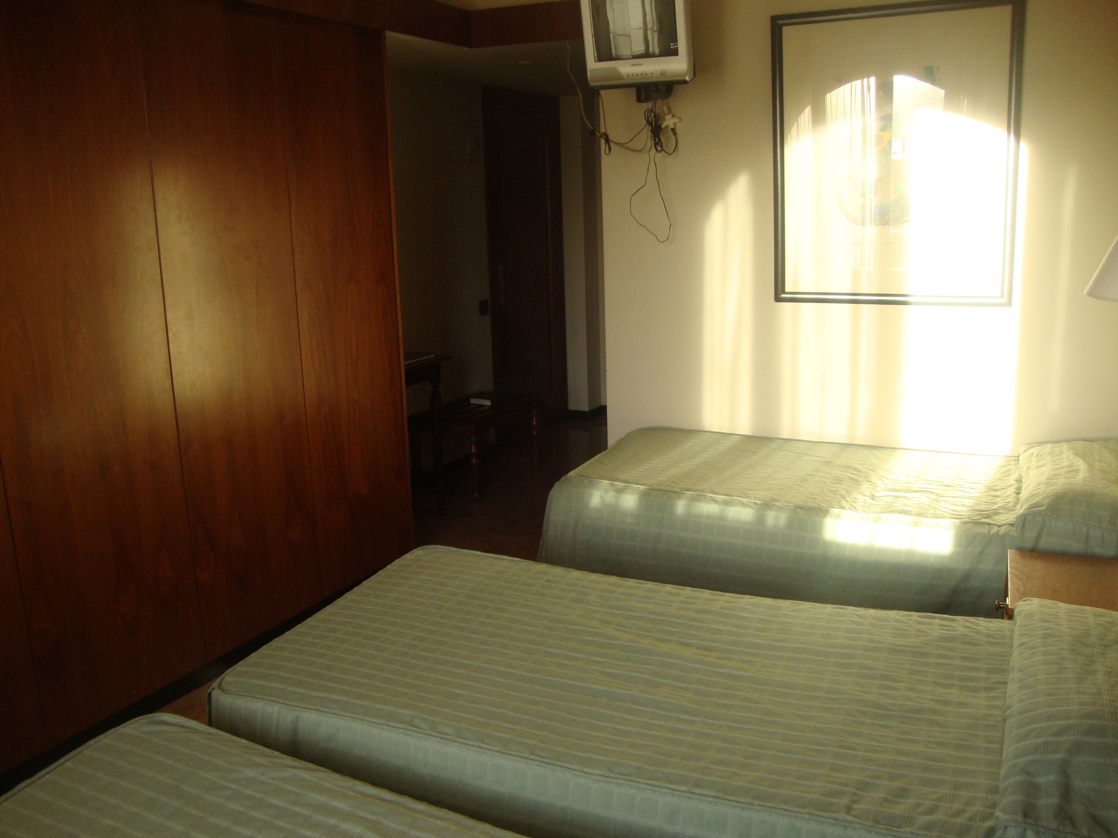 A room with two beds, wooden paneling, a ceiling fan, and a window with curtains.