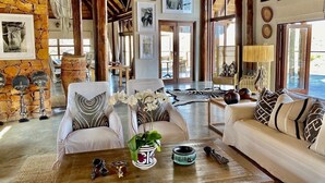 A spacious living area with a stone wall, two sofas with patterned cushions, a coffee table with decorative items, and a large window with a view.