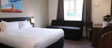 Habitación de hotel con una cama grande, un sofá, un escritorio y una ventana con cortinas.
