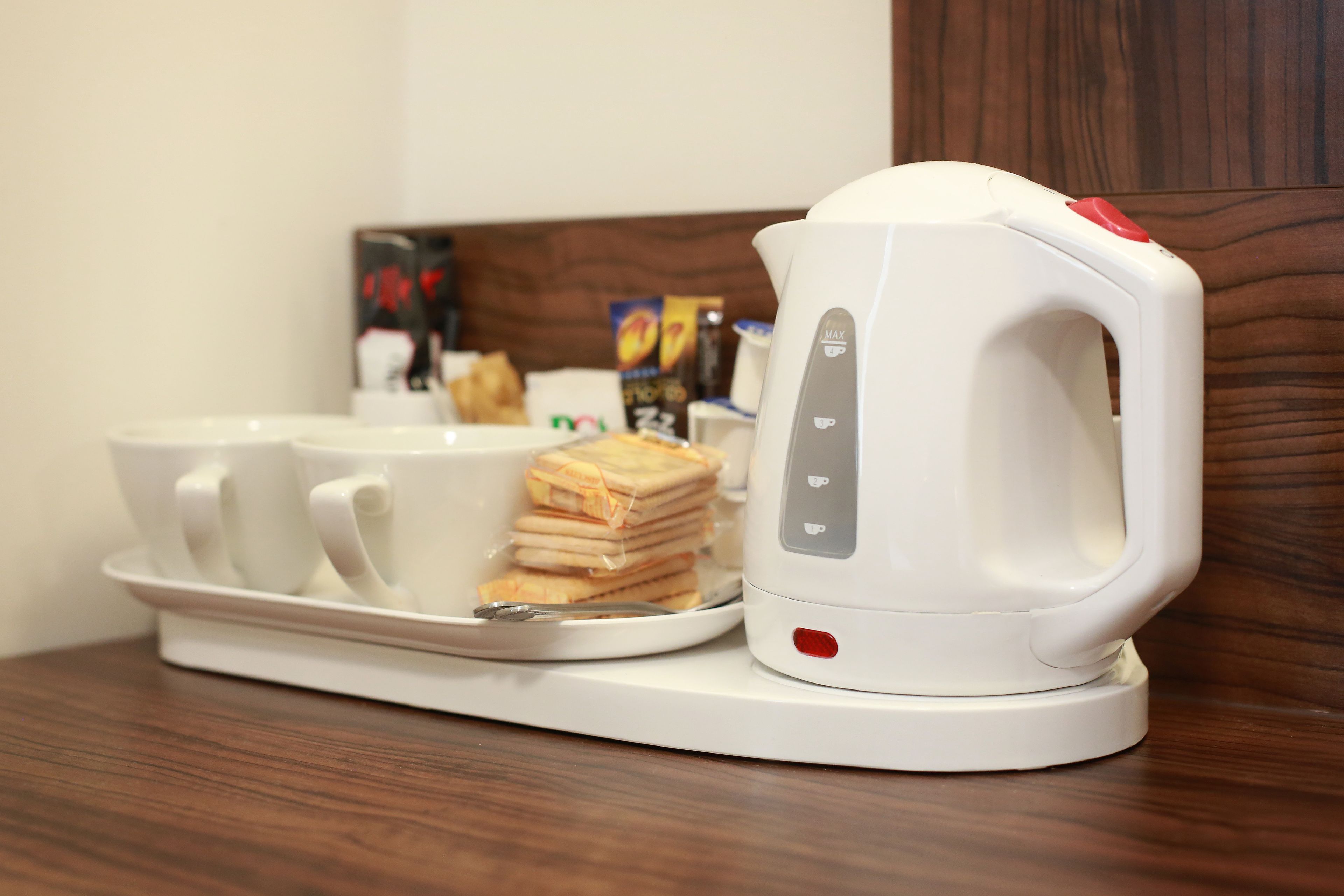 Une bouilloire électrique blanche, posée sur un plateau avec des tasses et une pile de tranches de pain.