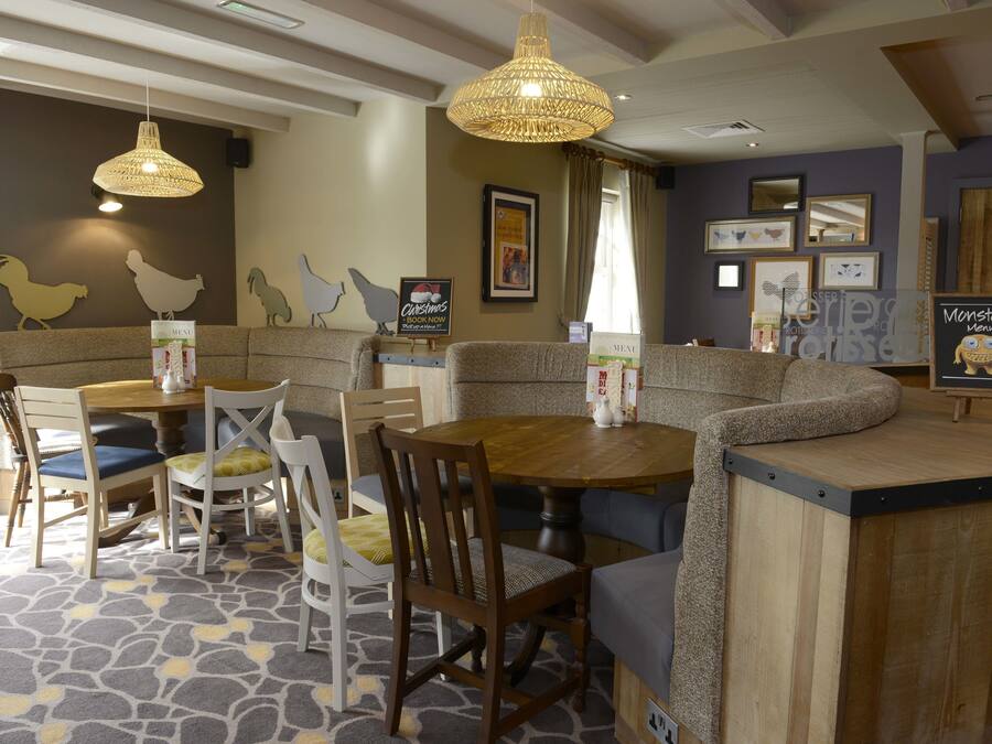A cozy restaurant with a wooden table and chairs, a bar area, and decorative wall art.