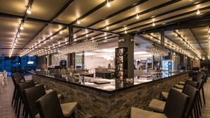 A bar area with a stone counter, wicker chairs, and overhead lighting. - Hotel Fontana (Vrnjacka Banja)