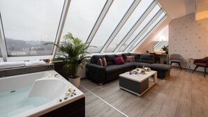 A modern living room with a large skylight, a sofa, a coffee table, and a bathtub. - Hotel Fontana (Vrnjacka Banja)