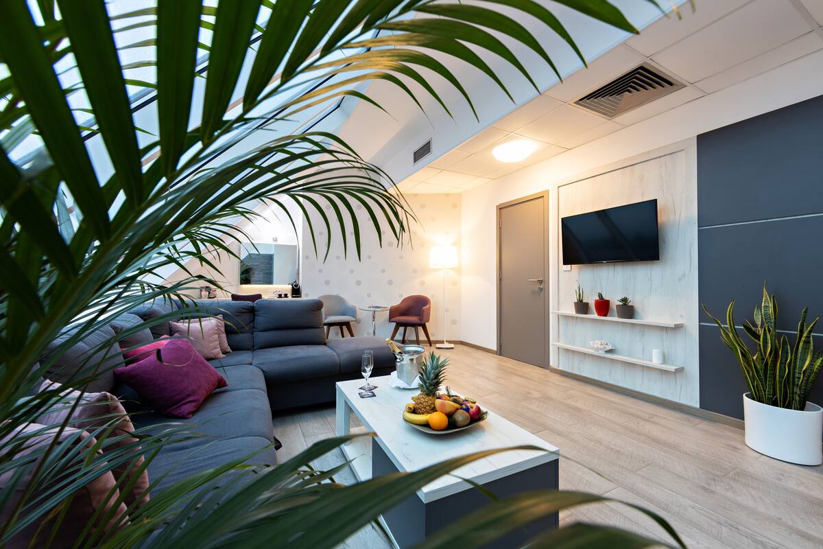 A modern living room with a sofa, coffee table, and a TV mounted on the wall.