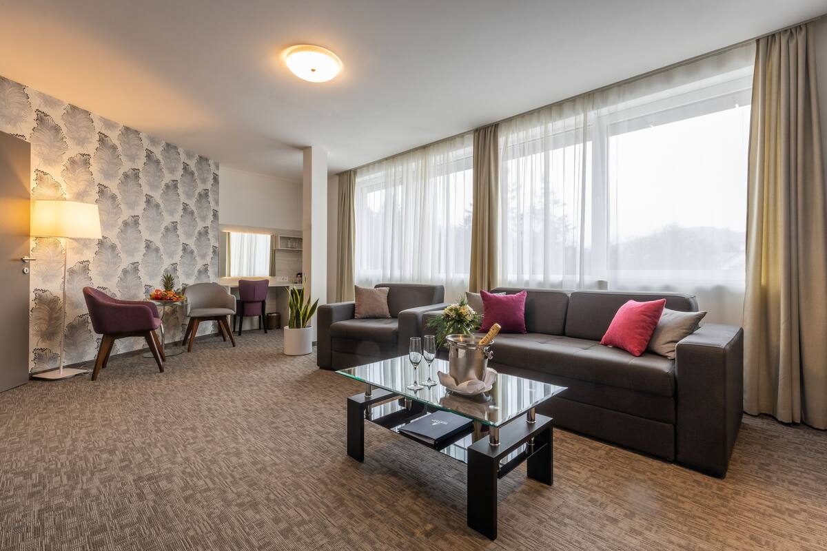 A modern living room with a glass coffee table, two sofas, and a dining area with chairs.