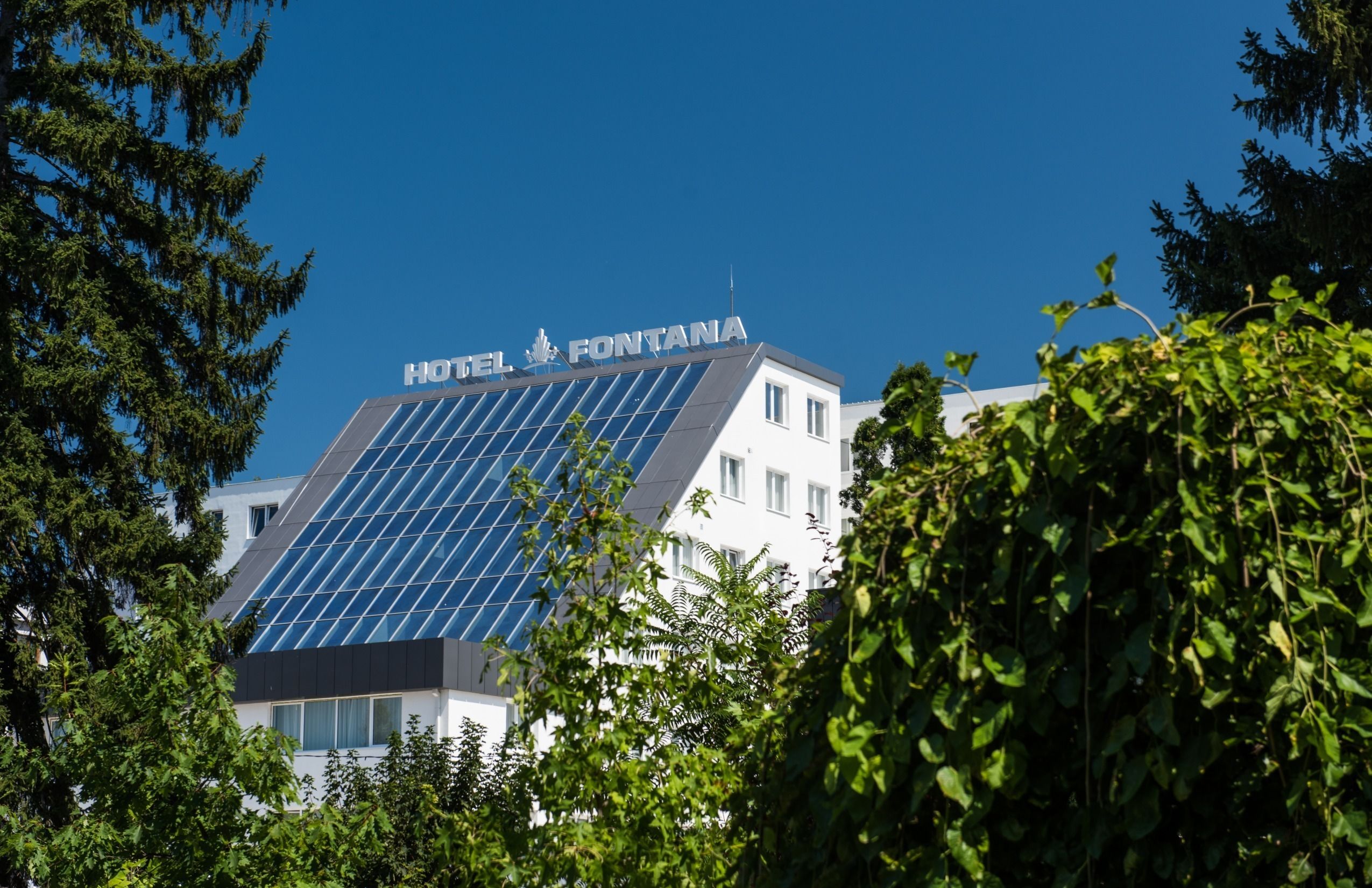 A hotel with a modern design, solar panels on the roof, and a sign that reads "HOTEL FONTANA".