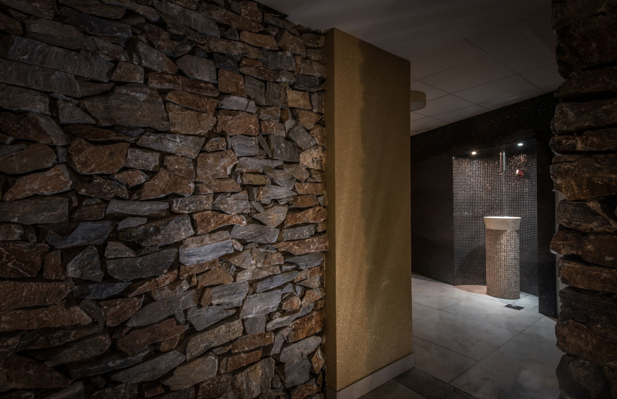 Un pasillo con pared de piedra y un pilar.