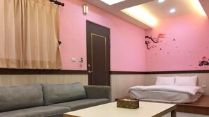 A room with a sofa, a bed, a table, and a door. - Seasons B&B (Liuqiu)
