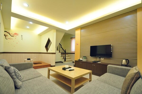 A modern living room with a flat-screen TV, a wooden coffee table, and two grey sofas. - Seasons B&B (Liuqiu)
