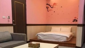 A small, cozy room with a bed, a sofa, and a table. - Seasons B&B (Liuqiu)