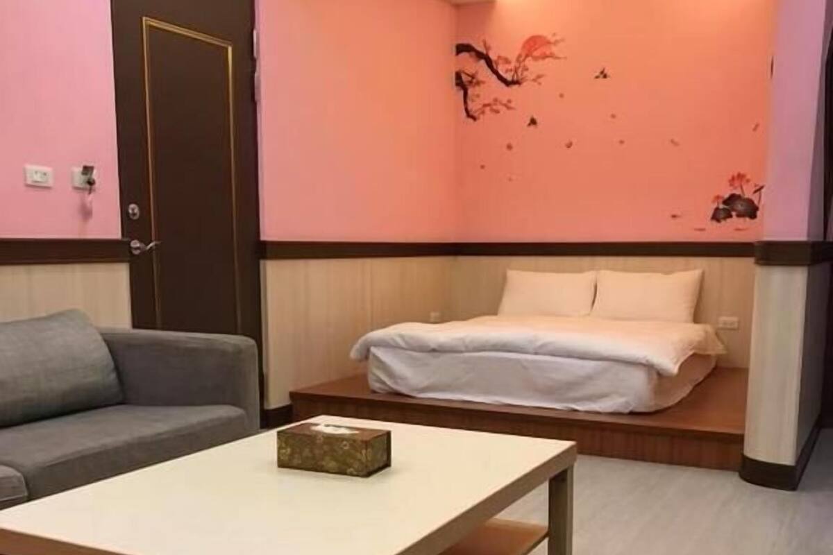 A small, cozy room with a bed, a sofa, and a table.
