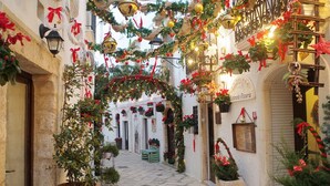 A narrow street with a festive archway decorated with greenery and red ribbons.