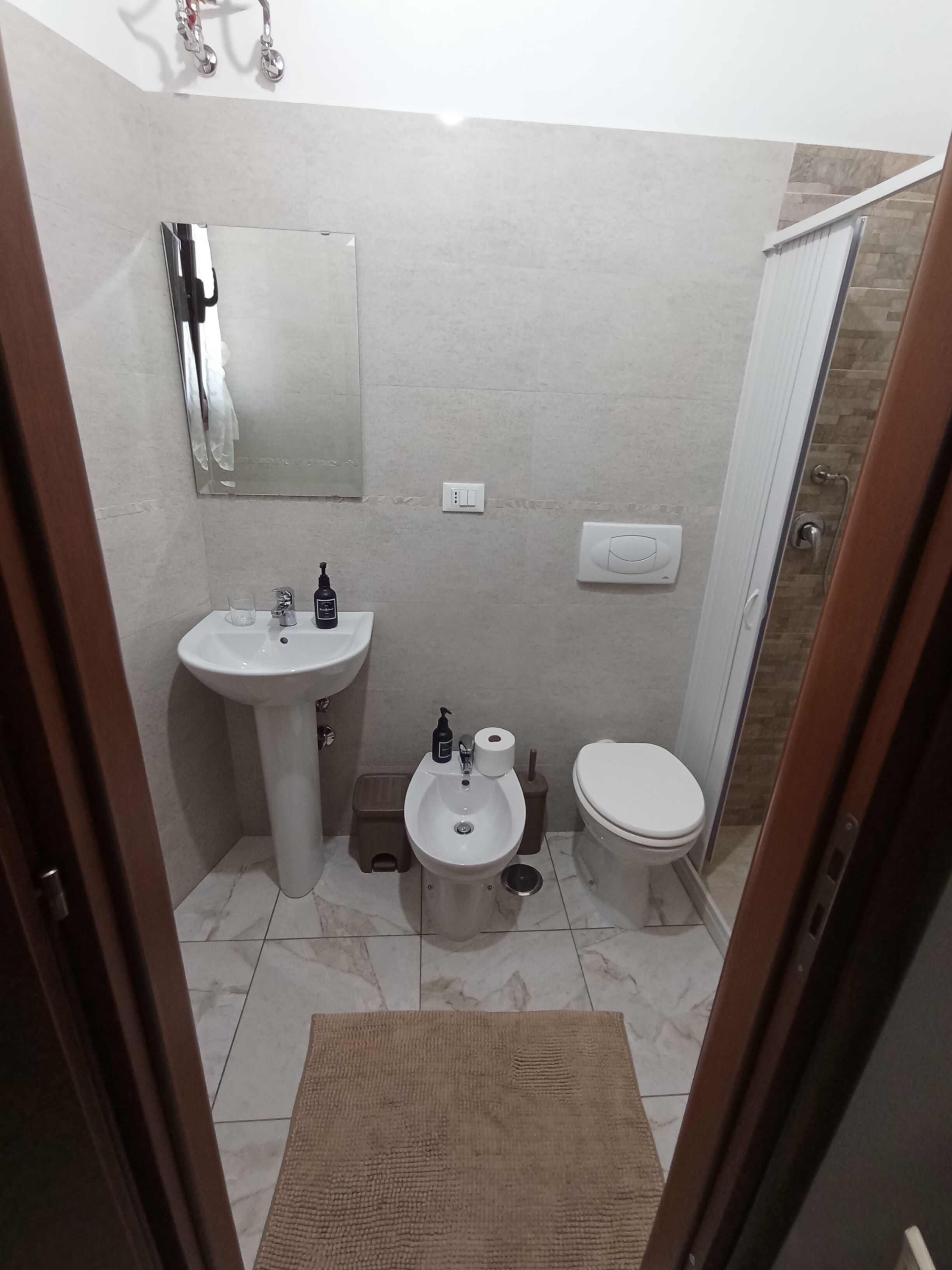 A small bathroom with a sink, toilet, and a mirror.
