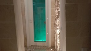 A staircase with patterned tiles leading to a door with a green-lit interior.